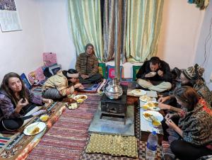 a group of people sitting around a table eating food at Mochilero Eyrie in Kaza