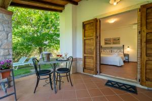 a patio with a table and chairs and a bed at Agriturismo Il Cavallino Saturnia in Semproniano