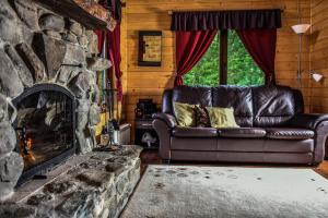 um sofá de couro numa sala de estar com lareira de pedra em The Little Mountain Cabin em Borlova