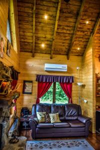 un sofá de cuero en una habitación con ventana en The Little Mountain Cabin, en Borlova