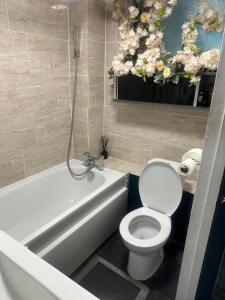 a bathroom with a white toilet and a bath tub at Charming Flat in North London in Edmonton