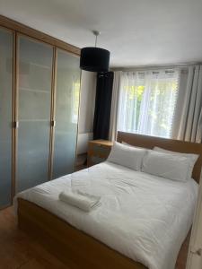 a bedroom with a bed with white sheets and a window at Charming Flat in North London in Edmonton