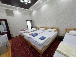 a bedroom with two beds and a red carpet at Dada guest house in Bukhara