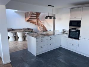 a kitchen with white cabinets and a living room at Chameleon House in Dornoch