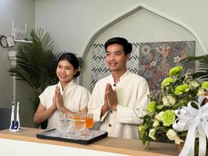 a man and woman standing behind a counter with their hands in prayer at Best House Luang Prabang in Luang Prabang