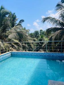 a blue swimming pool with palm trees in the background at Calangute house inn in Calangute