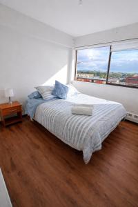 a white bedroom with a bed and a large window at Alojamiento Centro Osorno Plaza del Toro in Osorno