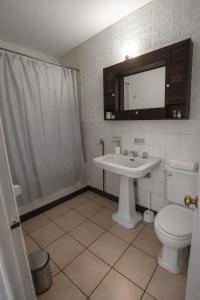 a bathroom with a sink and a toilet and a mirror at Alojamiento Centro Osorno Plaza del Toro in Osorno