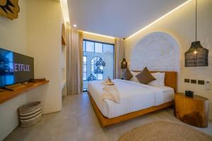 a bedroom with a large white bed and a tv at 2BR villa w- pool & beach access in Mengwi