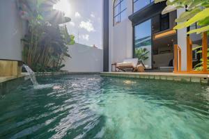 a swimming pool in front of a house at Breezy villa w- pool & beach access in Mengwi