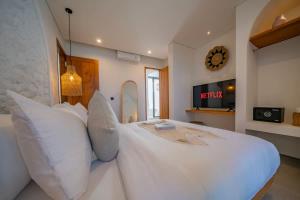 a bedroom with a white bed with pillows and a clock at Breezy villa w- pool & beach access in Mengwi +185 photos