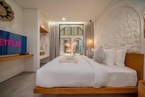 a bedroom with a large white bed and a television at Breezy villa w- pool & beach access in Mengwi
