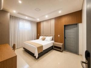a bedroom with a large bed and a door at Hotel El Shaddai in Pontes e Lacerda