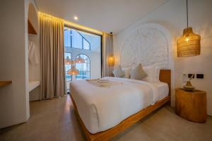 a bedroom with a large white bed and a large window at Breezy villa w- pool & beach access in Mengwi