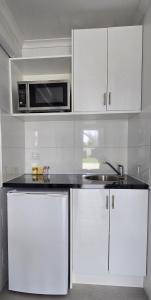 a kitchen with white cabinets and a microwave at Albatross Motel in Lakes Entrance