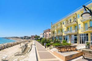 a street with benches and buildings next to the ocean at President Frontemare - Agenzia Cocal in Caorle