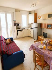 a kitchen with a table and a blue couch at President Frontemare - Agenzia Cocal in Caorle