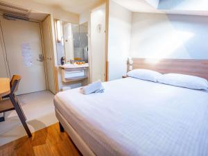 a bedroom with a large white bed and a bathroom at ibis budget Metz Sud in Augny