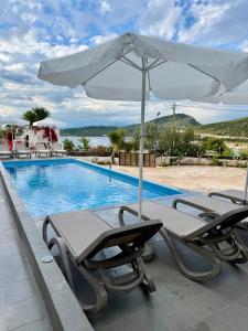 two lounge chairs and an umbrella next to a swimming pool at Full Moon Apartments in Ksamil