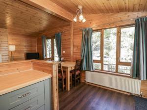 a log cabin kitchen with a desk and a table at Elm Lodge in Keswick