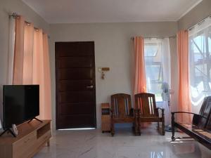 a living room with a flat screen tv and chairs at A Peaceful House in Mexico