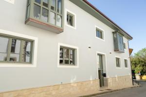 a white house with green windows at Apartamentos Villa De Comillas in Comillas