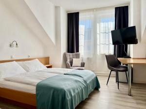 a bedroom with a bed and a desk and a television at City Hotel Neuwied in Neuwied