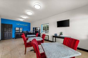 a waiting room with red chairs and tables and a tv at Rodeway Inn in Dilley