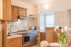 a kitchen with wooden cabinets and a stove top oven at Casa Roberto - piano terra con giardino in Levico Terme