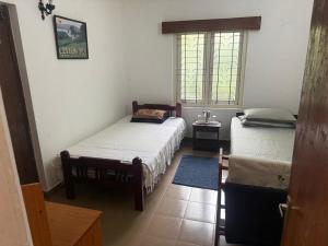 a room with two beds and a window at Verandah 46 Homestay Kandy in Katugastota