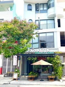 an umbrella in front of a building with tables and chairs at Bống's Homesray and café in Ho Chi Minh City