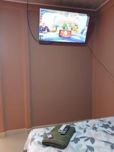 a tv on a wall above a bed with remotes at Cabinas El Mirador in Canoas
