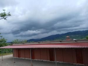 a red building with a red roof with mountains in the background at Cabinas El Mirador in Canoas