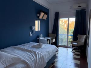 a blue bedroom with a bed and a window at Hotel Avra in Egina