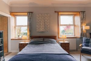 a bedroom with a bed and two windows at BARHOLM CROFT Holiday Cottage in Creetown