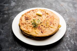 a white plate with a stack of pancakes on a table at Star Spandan in New Town