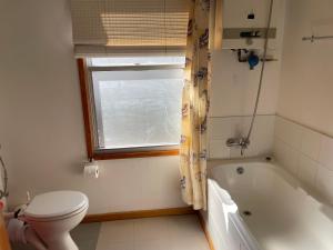 a bathroom with a toilet and a tub and a window at lagoon Breeze in Langebaan