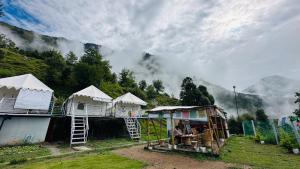 a group of tents with a view of a mountain at Sari Highlands chopta Offbeat campsite in Ukhimath