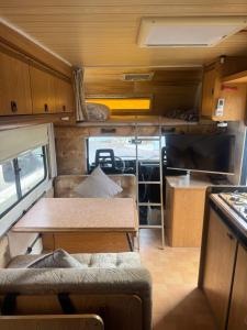 an interior of an rv with a table and a tv at Caravans through the nature in Mikhmoret