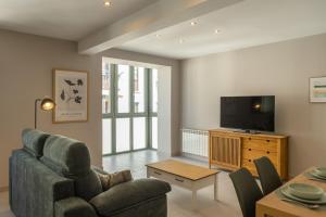 a living room with a couch and a tv at Apartamentos Villa De Comillas in Comillas