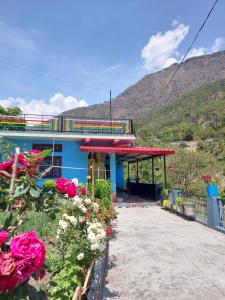 a blue building with flowers in front of it at PeaceVibe Homestay in Uttarkāshi