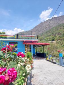 a blue building with flowers in front of it at PeaceVibe Homestay in Uttarkāshi