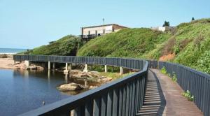 a bridge over a body of water with a house on a hill at Mangrove Beach Estate Boboyi in Port Shepstone