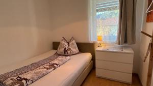 a small bedroom with a bed and a dresser and a window at Wohlfühlapartments Steiner in Altmünster