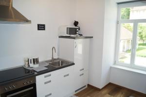 a kitchen with white cabinets and a sink and a window at Loft Style Studio - historic old town in Villingen-Schwenningen