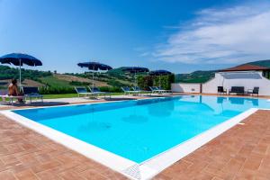a large swimming pool with chairs and umbrellas at Agriturismo Il Cavallino Saturnia in Semproniano