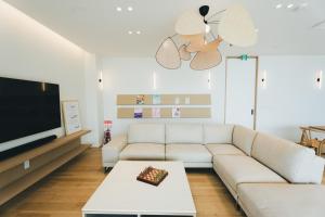 a living room with a white couch and a tv at SHIMASTREAM house in Shodoshima