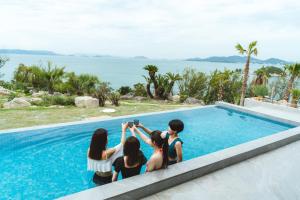 a group of girls sitting next to a swimming pool at SHIMASTREAM house in Shodoshima