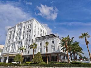 a white building with palm trees in front of it at Tây Nam 2 Hotel in Can Tho