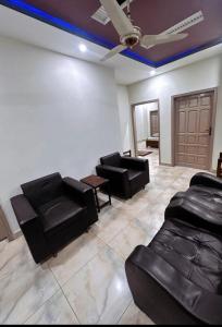 a living room with black leather furniture and a ceiling at Khushal Residence in Peshawar